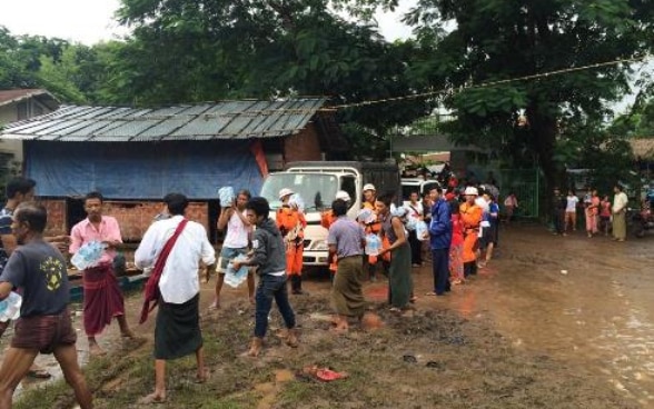 Emergency workers and civilians pass bottles of water along a human chain.