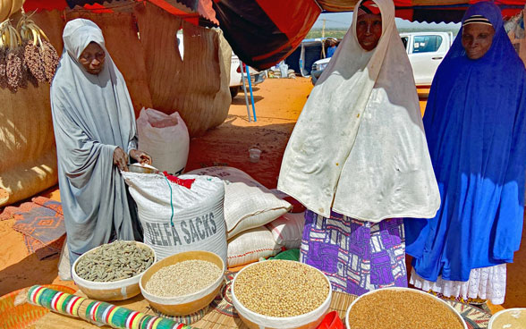 Veiled women busy themselves around a stall selling various grains in a tent in Niger.