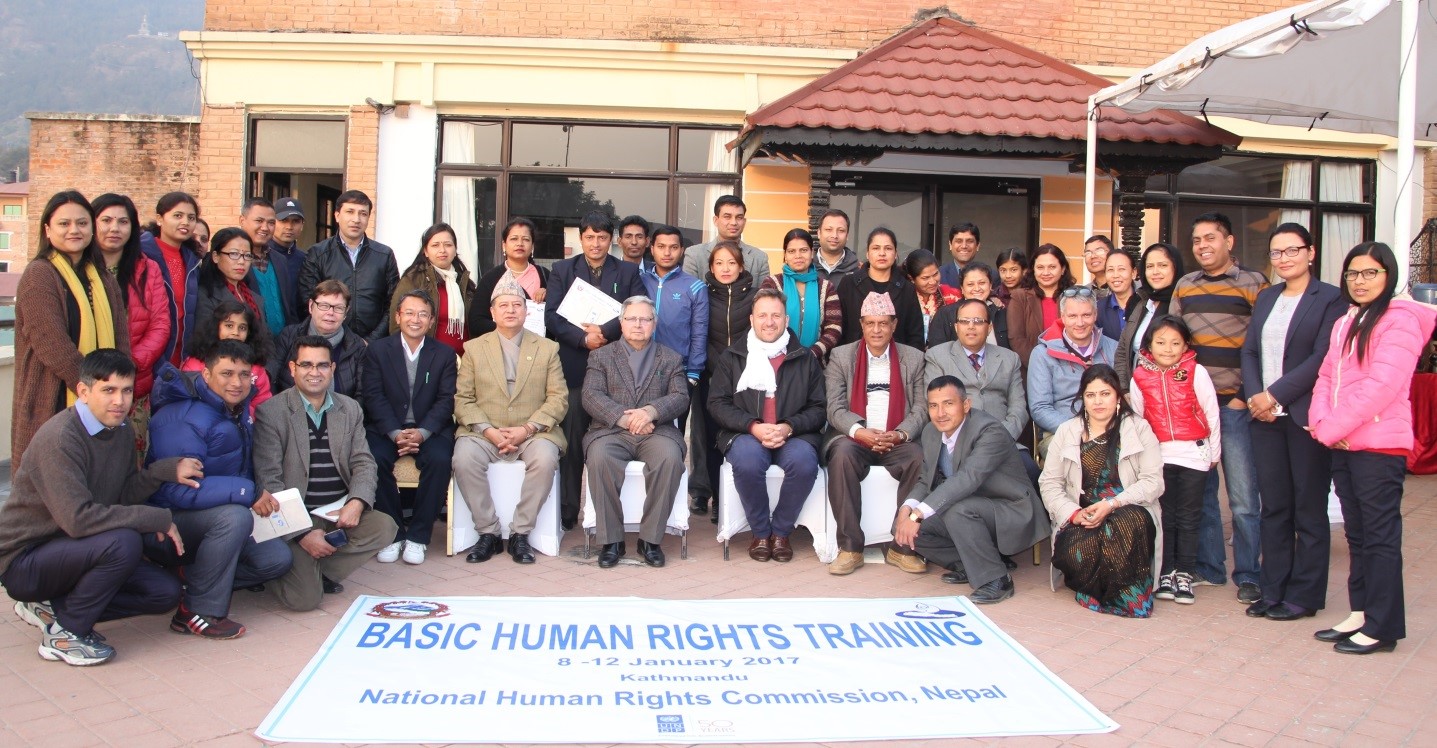 A group of women and men pose for a photo in front of a banner reading 'Basic Human Rights Training'.