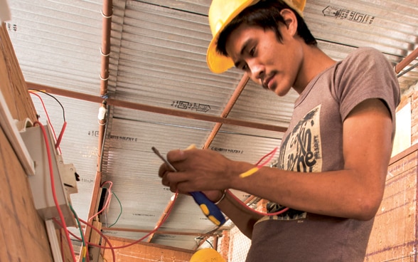 Trois jeunes apprentis suivent une formation d’électricien au Népal.