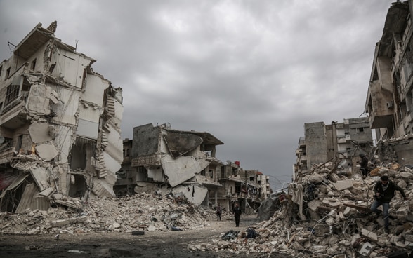 Menschen gehen durch die Trümmer der von Luftangriffen getroffenen syrischen Stadt Idlib.