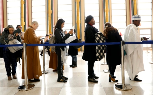 Donne e uomini stanno aspettando la registrazione in una sala alta.