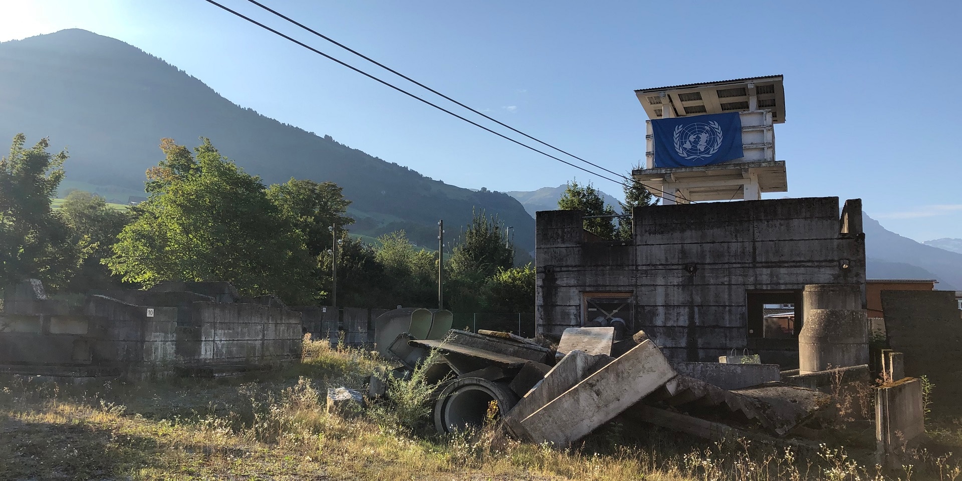 Une tour blanche en bois arbore le drapeau de l’ONU dans un paysage de montagne idyllique, aux environs de Stans.