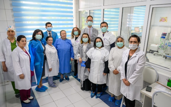 Group of men and women in medical attire visiting the maternity ward.