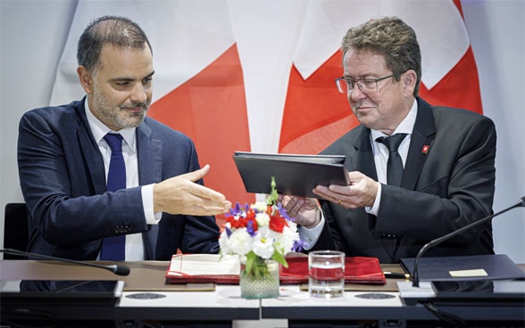 Le conseiller fédéral Albert Rösti et le ministre français Laurent Saint-Martin en train de signer à Genève deux accords sur les eaux du Rhône et du lac Léman.