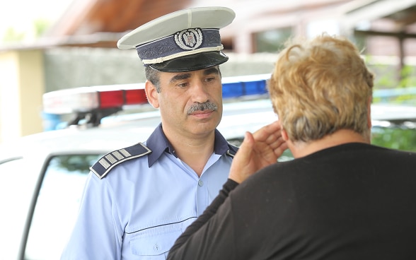 A policeman listens to a woman.